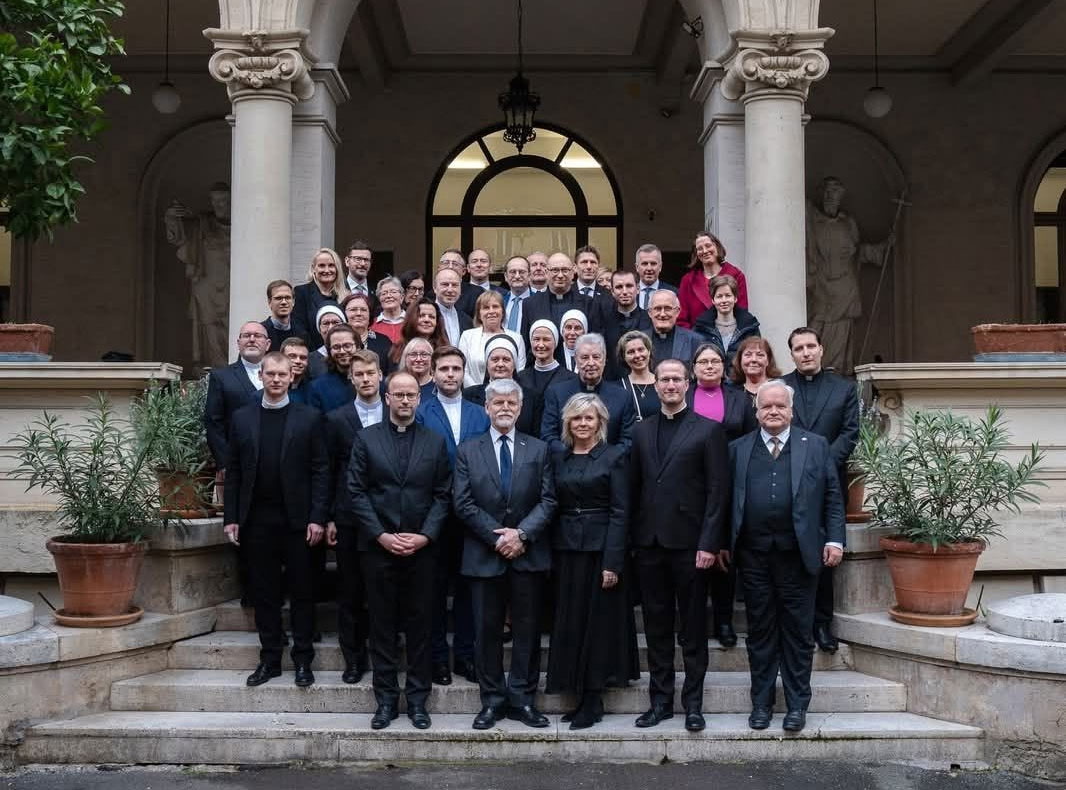 Skupinová fotografie hostů a zaměstnanců na schodech historické budovy ústavu.
